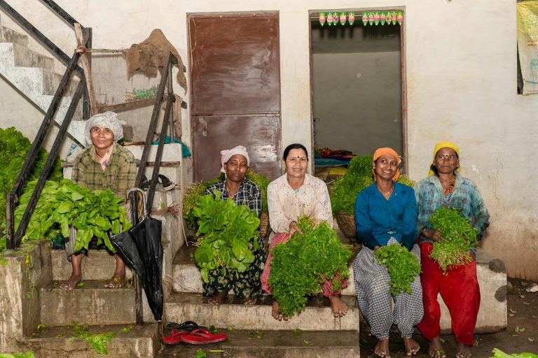 Group of women farmers in Nagpur, India, holding fresh vegetables, showcasing agricultural work.