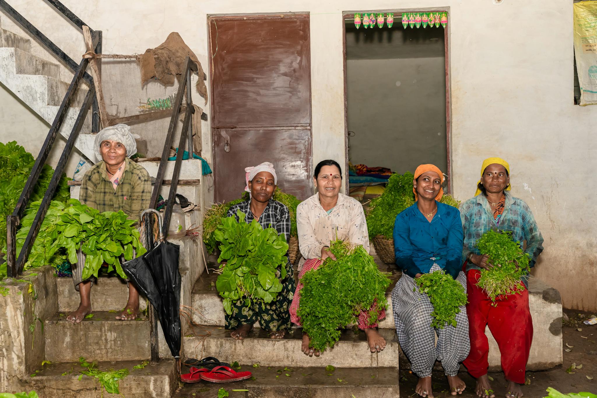 Group of women farmers in Nagpur, India, holding fresh vegetables, showcasing agricultural work.
